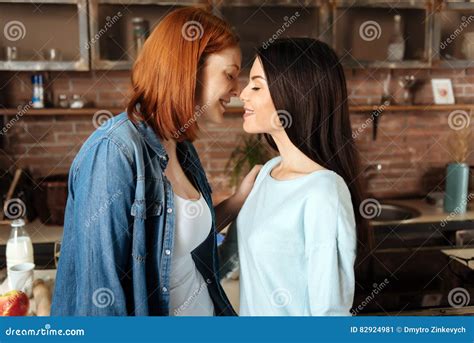 Two beautiful brunette lesbian women kiss sensually. Stock Photo